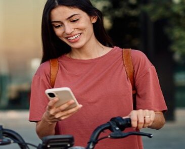 Frau mit Smartphone am Fahrrad.