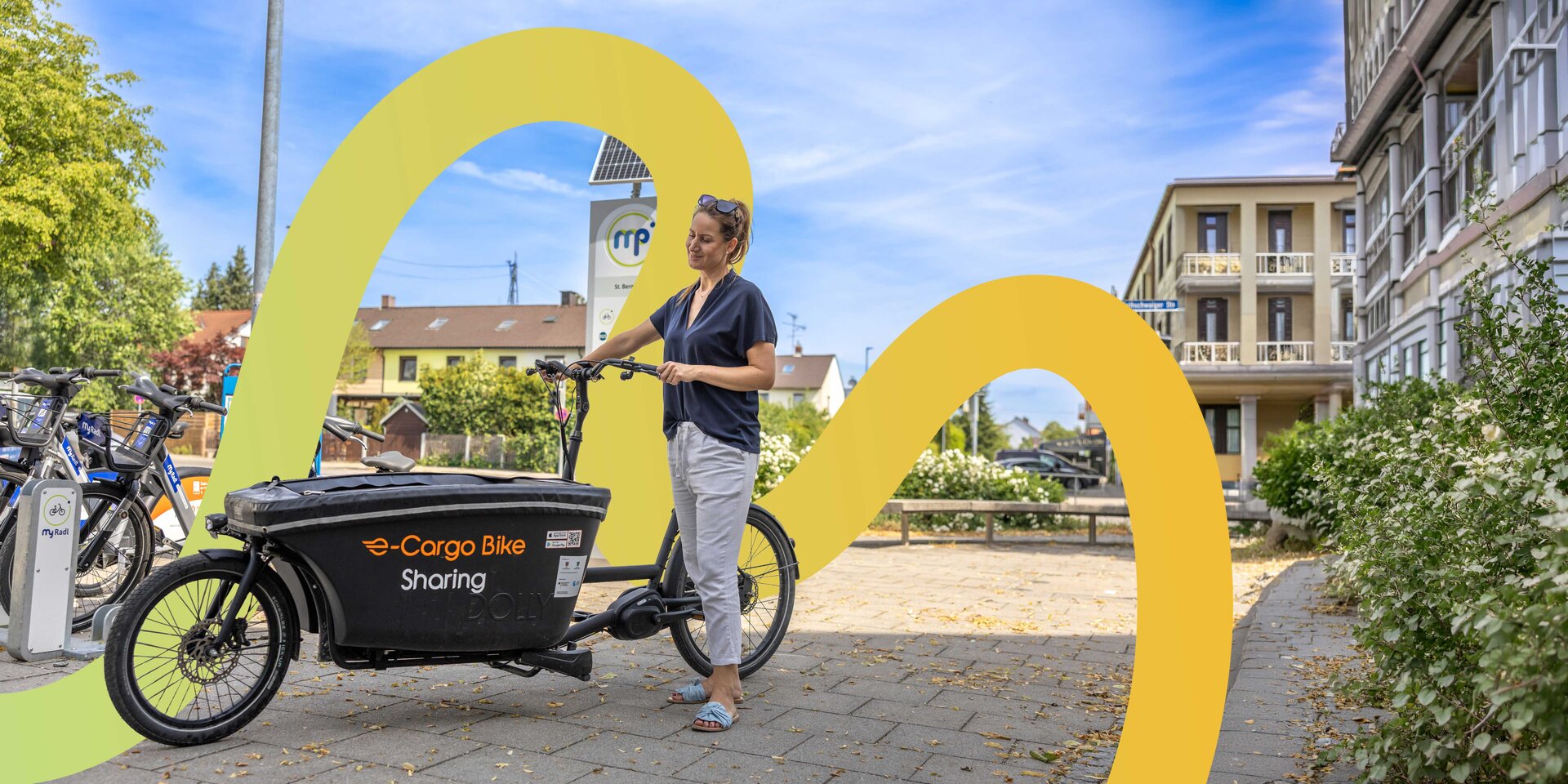 Frau mit Leih-Lastenrad an einer Mobilitätsstation.